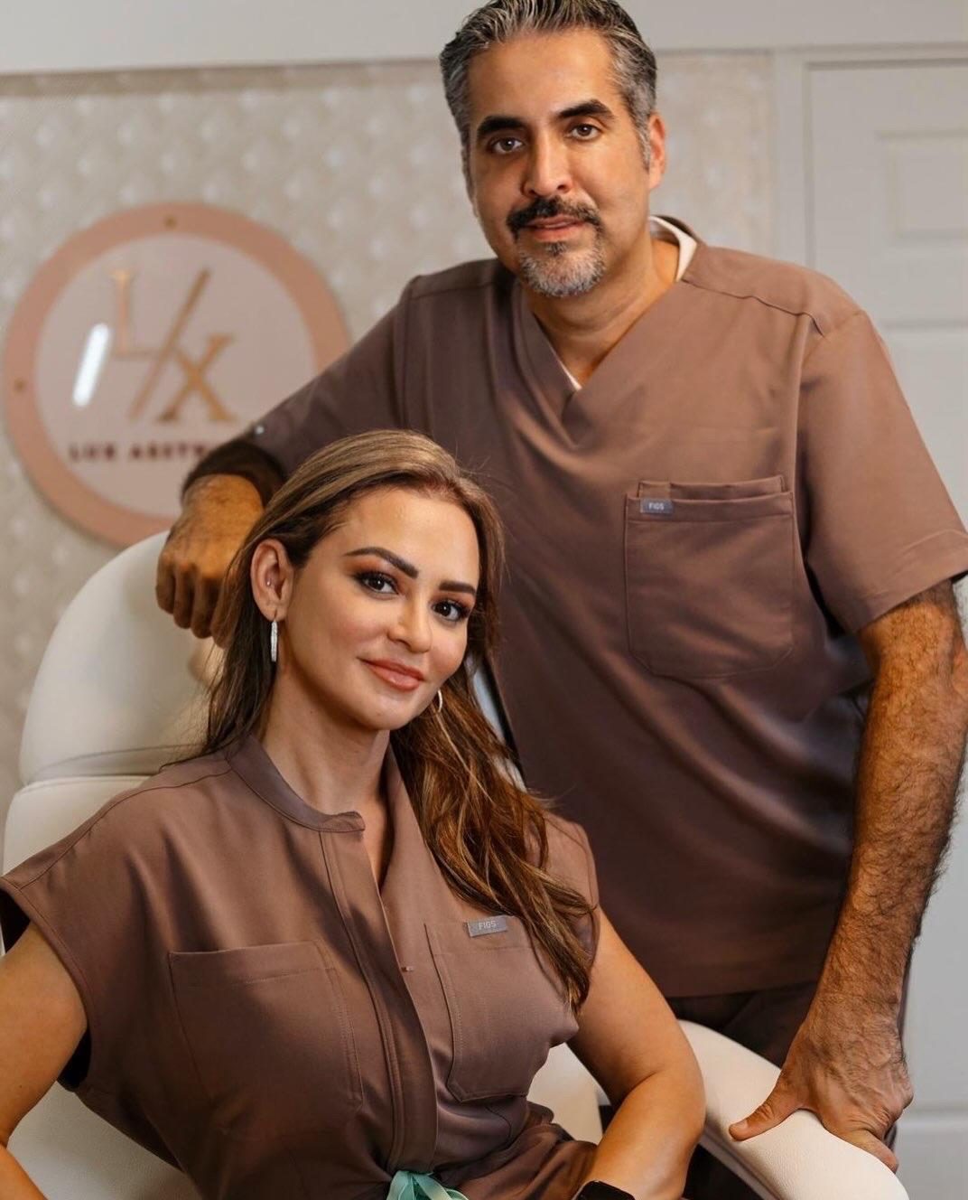 Priscilla Peña seated with her husband Victor Peña, RPA, standing behind her, both in brown scrubs